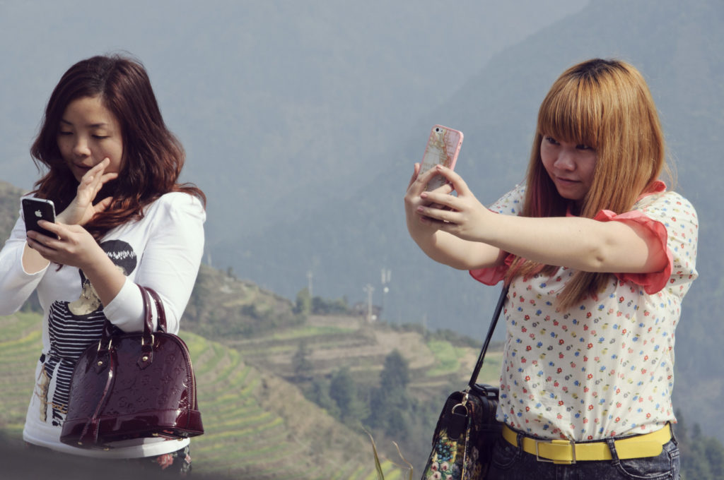 Dos chicas toman un selfie con un precipicio de fondo.